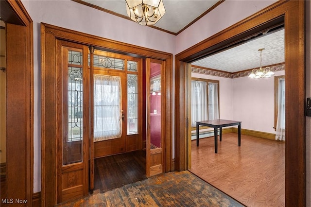 foyer with crown molding, plenty of natural light, dark hardwood / wood-style floors, and an inviting chandelier