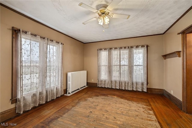 empty room with ceiling fan, a healthy amount of sunlight, dark hardwood / wood-style flooring, and radiator heating unit