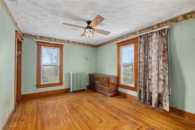 spare room featuring light parquet flooring, plenty of natural light, radiator, and ceiling fan