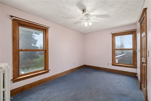 empty room featuring ceiling fan and dark carpet