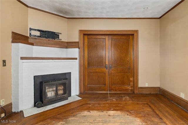 unfurnished living room featuring a textured ceiling, dark hardwood / wood-style floors, and ornamental molding