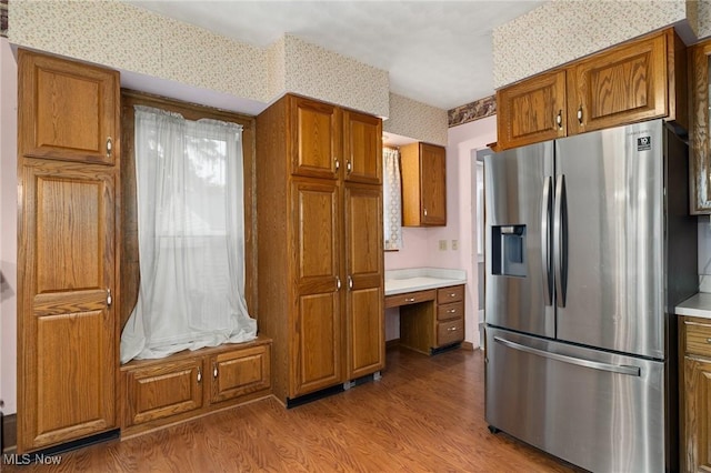 kitchen with stainless steel fridge with ice dispenser, built in desk, and light hardwood / wood-style floors