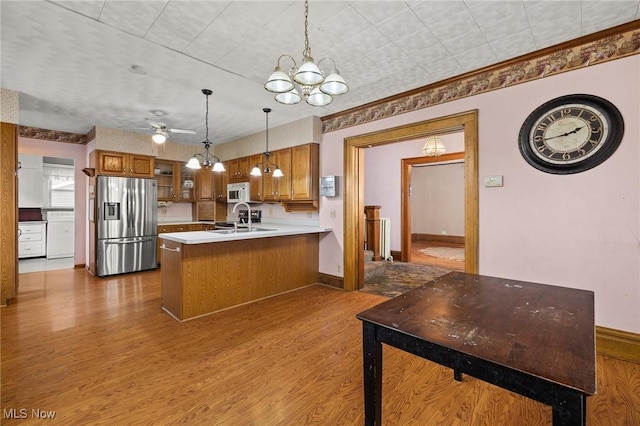 kitchen with stainless steel fridge with ice dispenser, light hardwood / wood-style flooring, kitchen peninsula, pendant lighting, and ceiling fan with notable chandelier