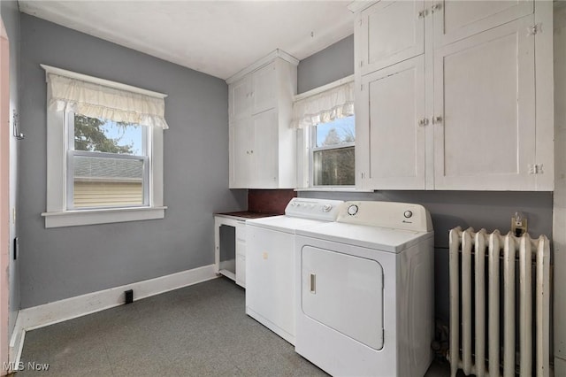 laundry room featuring washing machine and clothes dryer, radiator heating unit, cabinets, and plenty of natural light