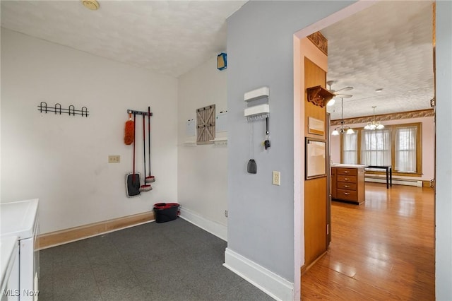 hallway featuring an inviting chandelier, hardwood / wood-style flooring, and a baseboard radiator