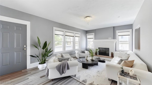 living room featuring a fireplace, light hardwood / wood-style floors, and an inviting chandelier