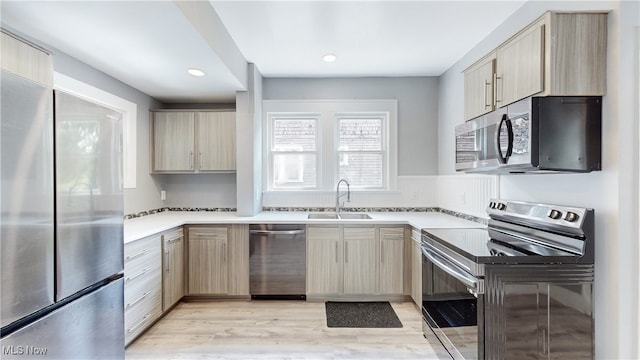 kitchen featuring light brown cabinetry, stainless steel appliances, and sink