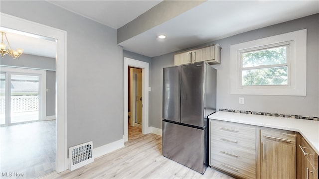 kitchen featuring stainless steel fridge, light hardwood / wood-style flooring, a wealth of natural light, and pendant lighting