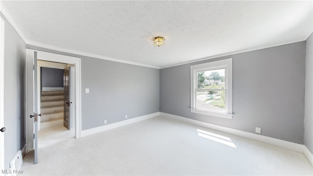 carpeted empty room with a textured ceiling and crown molding