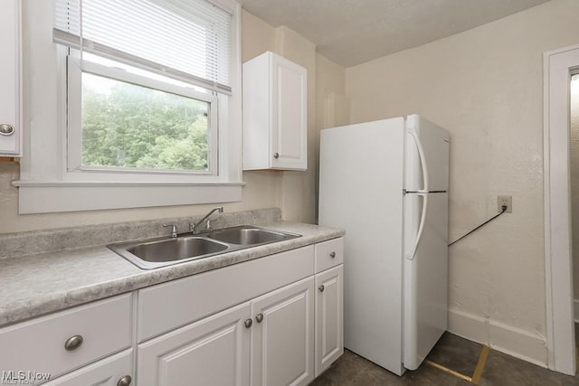 kitchen featuring white cabinets, sink, and white fridge