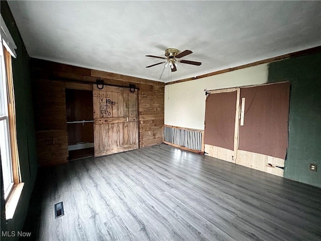 unfurnished bedroom with wood walls, ceiling fan, and hardwood / wood-style flooring