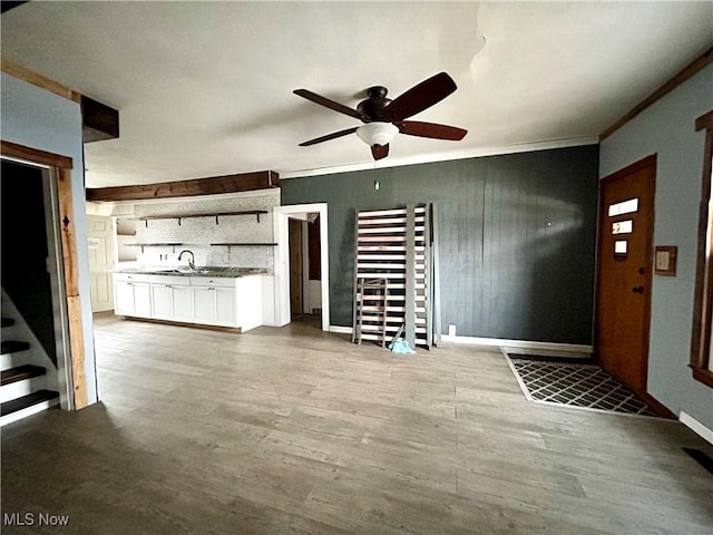 unfurnished living room featuring hardwood / wood-style flooring, ceiling fan, crown molding, and sink