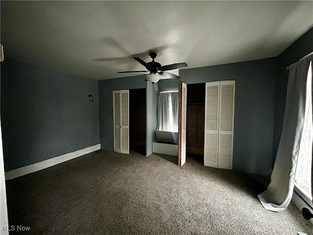 unfurnished bedroom with carpet, ceiling fan, and multiple closets