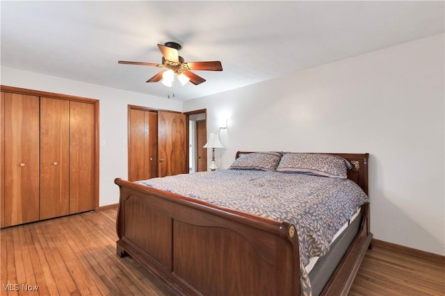 bedroom featuring multiple closets, ceiling fan, and wood-type flooring