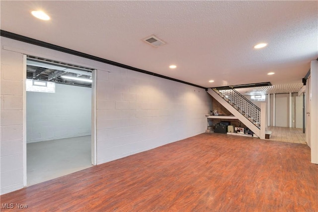 basement featuring a textured ceiling and hardwood / wood-style flooring