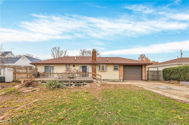 rear view of house featuring a deck, a garage, and a lawn