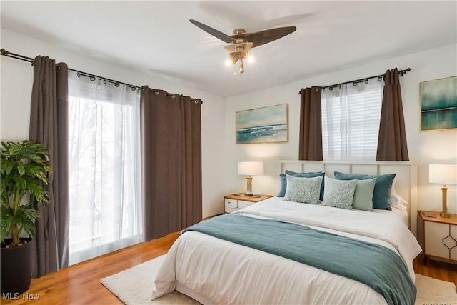 bedroom featuring hardwood / wood-style floors, ceiling fan, and multiple windows