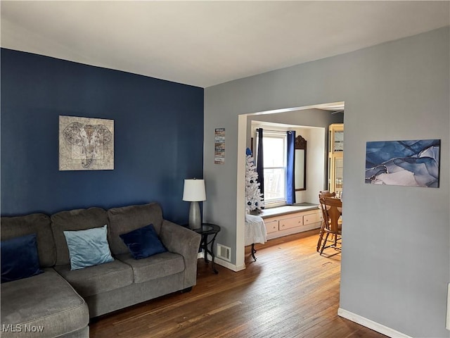 living room with wood finished floors, visible vents, and baseboards