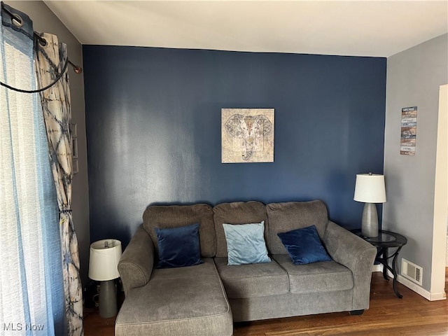 living room with visible vents, baseboards, and wood finished floors