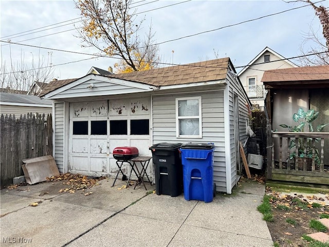 detached garage featuring driveway and fence