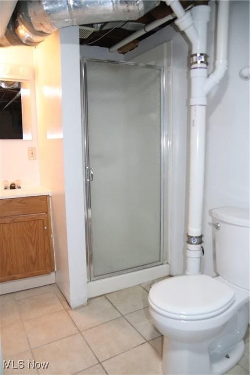 bathroom with tile patterned floors, a shower with door, vanity, and toilet