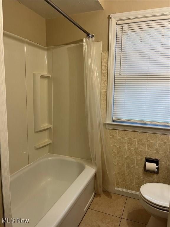 bathroom featuring tile patterned floors, toilet, tile walls, and shower / tub combo with curtain