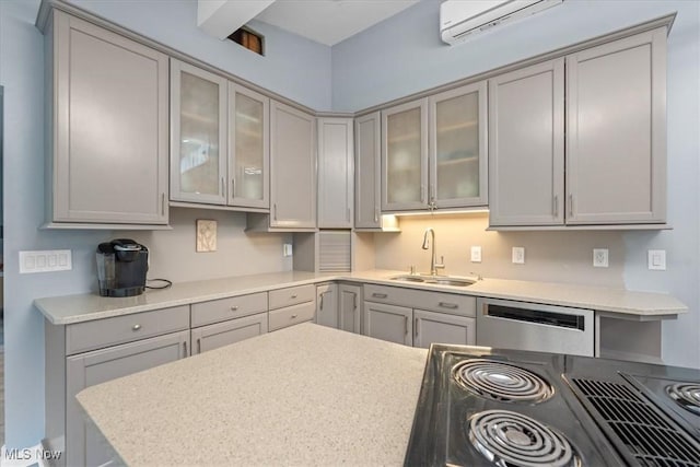 kitchen with gray cabinetry, an AC wall unit, sink, stainless steel dishwasher, and light stone counters