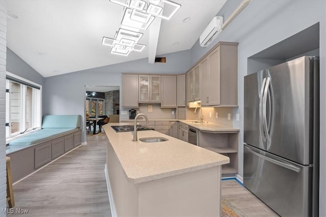 kitchen featuring a kitchen island with sink, stainless steel appliances, lofted ceiling, and light wood-type flooring