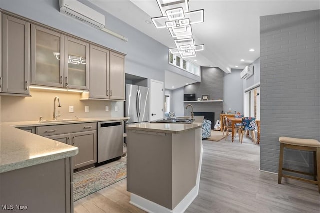 kitchen with light wood-type flooring, stainless steel appliances, an AC wall unit, and sink