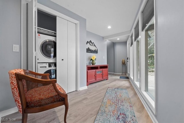 hallway with light hardwood / wood-style flooring and stacked washing maching and dryer