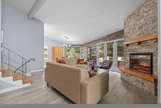 living room featuring vaulted ceiling with beams, light wood-type flooring, and a fireplace