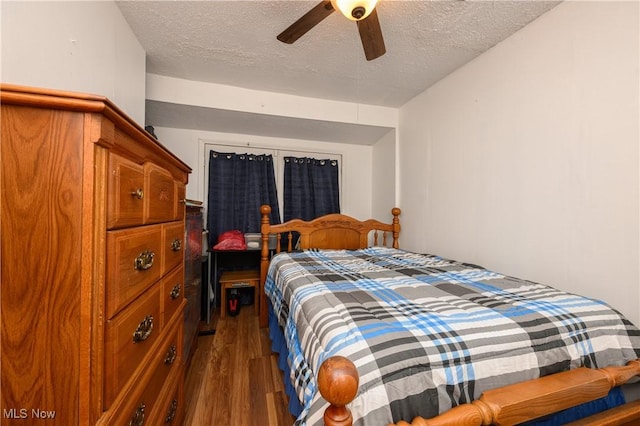 bedroom with ceiling fan, dark hardwood / wood-style flooring, and a textured ceiling