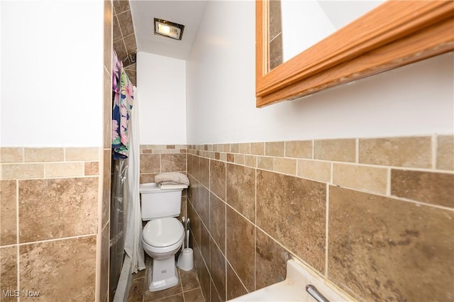 bathroom with tile patterned floors, toilet, and tile walls