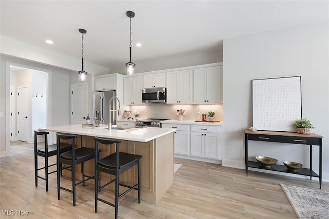 583 Iris Pl, Aurora, OH 44202 - kitchen featuring appliances with stainless steel finishes, a sink, light wood-style flooring, a kitchen island with sink, and recessed lighting