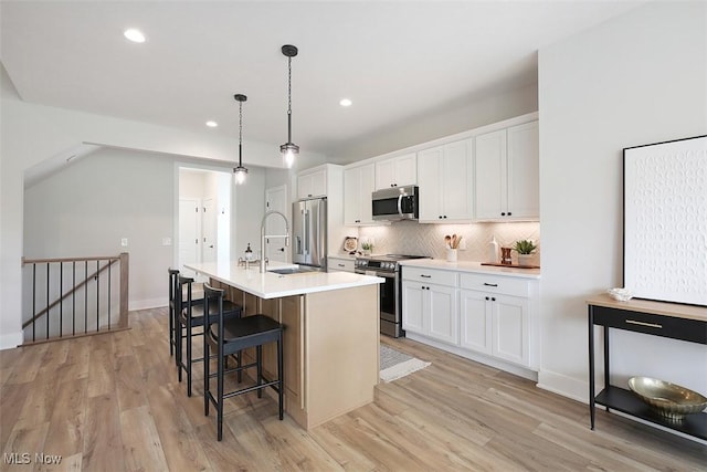 583 Iris Pl, Aurora, OH 44202 - kitchen with stainless steel appliances, white cabinets, a kitchen island with sink, a breakfast bar area, and a sink