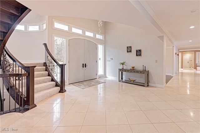 foyer with light tile patterned floors and ornamental molding