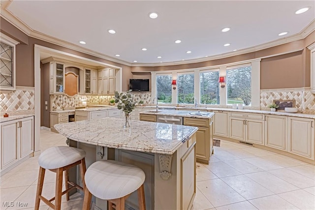 kitchen featuring backsplash, light stone counters, dishwasher, a kitchen island, and a breakfast bar area