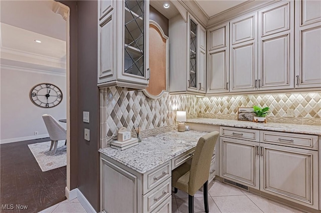 kitchen with light hardwood / wood-style floors, light stone countertops, crown molding, and tasteful backsplash