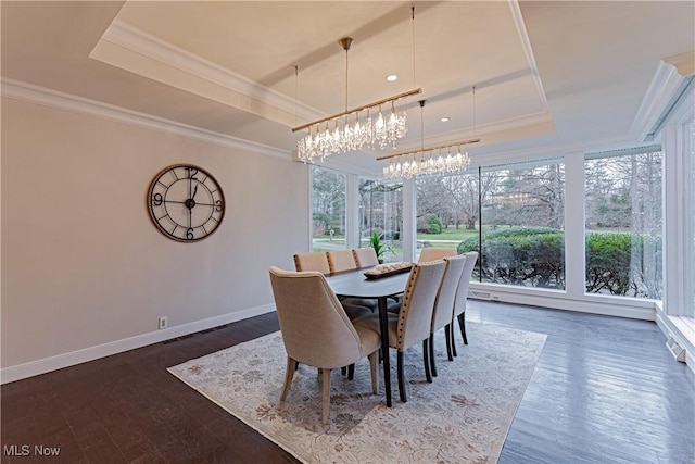 dining room with a chandelier, dark hardwood / wood-style flooring, a tray ceiling, and a healthy amount of sunlight