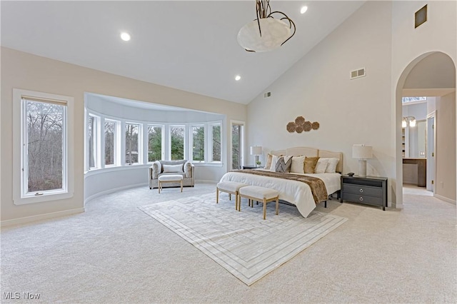 carpeted bedroom featuring ensuite bath and high vaulted ceiling