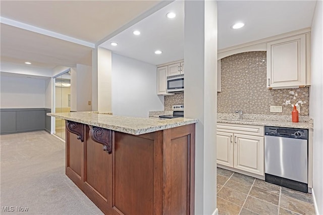 kitchen with light carpet, appliances with stainless steel finishes, backsplash, and light stone countertops