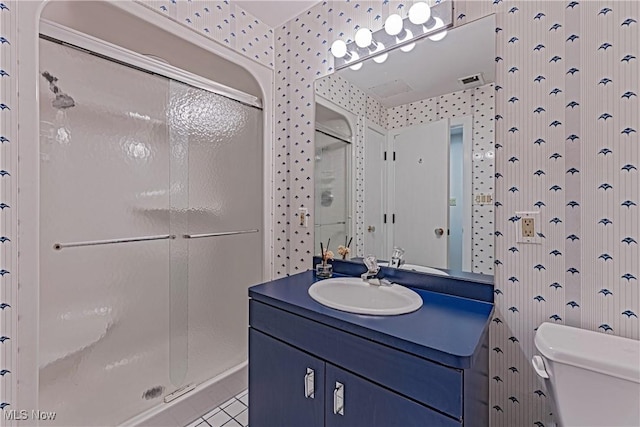 bathroom featuring tile patterned flooring, vanity, toilet, and a shower with door