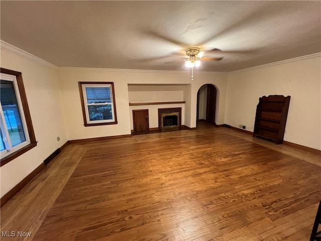 unfurnished living room featuring a fireplace, hardwood / wood-style flooring, ceiling fan, and ornamental molding