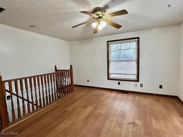 empty room featuring a textured ceiling, light hardwood / wood-style flooring, and ceiling fan