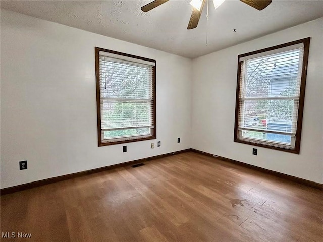 spare room with hardwood / wood-style floors, plenty of natural light, and a textured ceiling