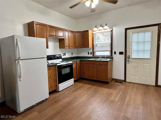 kitchen with white appliances, hardwood / wood-style flooring, ceiling fan, and sink