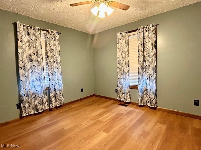 empty room with ceiling fan, hardwood / wood-style floors, and a textured ceiling