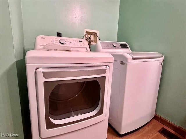 laundry area featuring washing machine and dryer and light hardwood / wood-style flooring