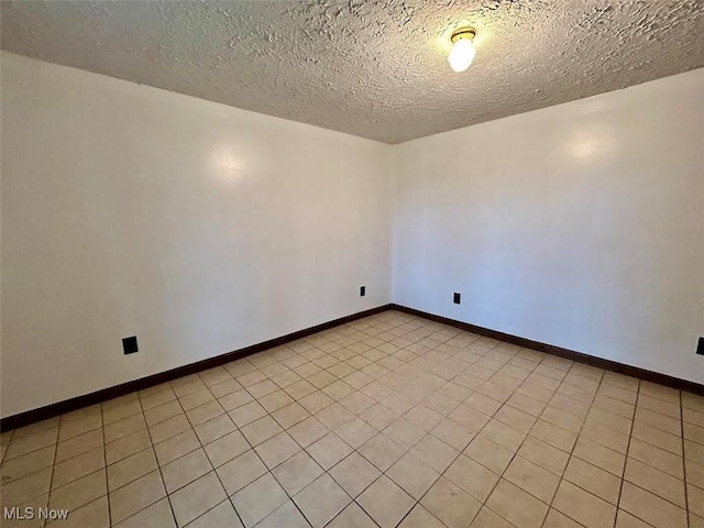 unfurnished room featuring a textured ceiling and light tile patterned flooring