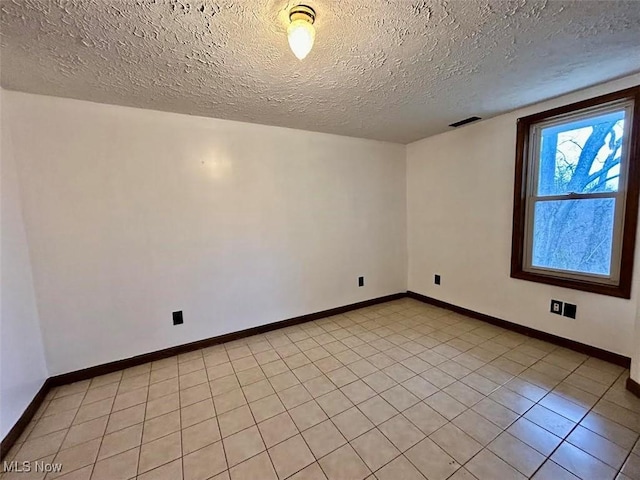 unfurnished room with light tile patterned floors and a textured ceiling